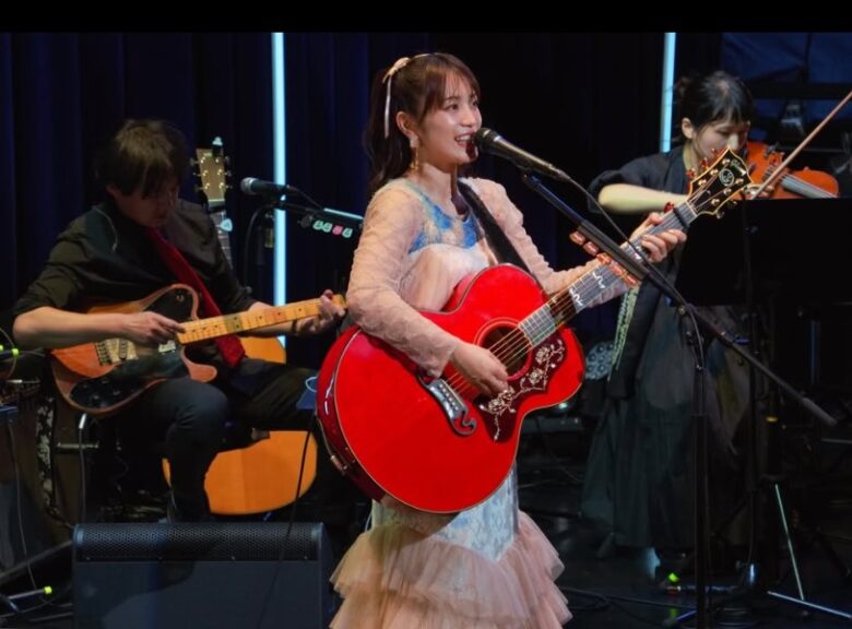 miwaがギターを持って歌いステージに立っている画像