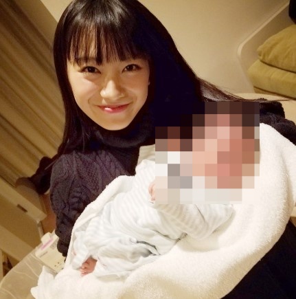 赤ちゃんのベッドの横で微笑むmiwaの画像