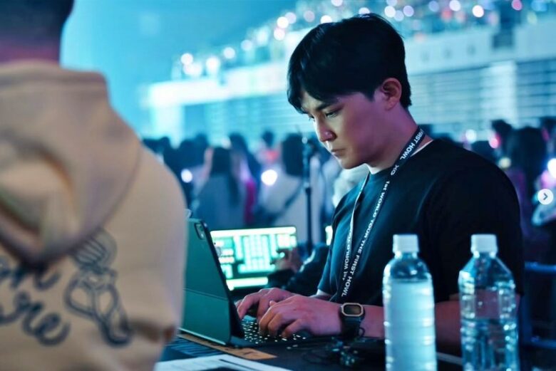 ライブ会場内でパソコンで仕事をしているXGサイモンの画像