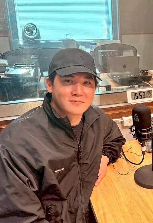 放送ブースで微笑むXGサイモンの画像