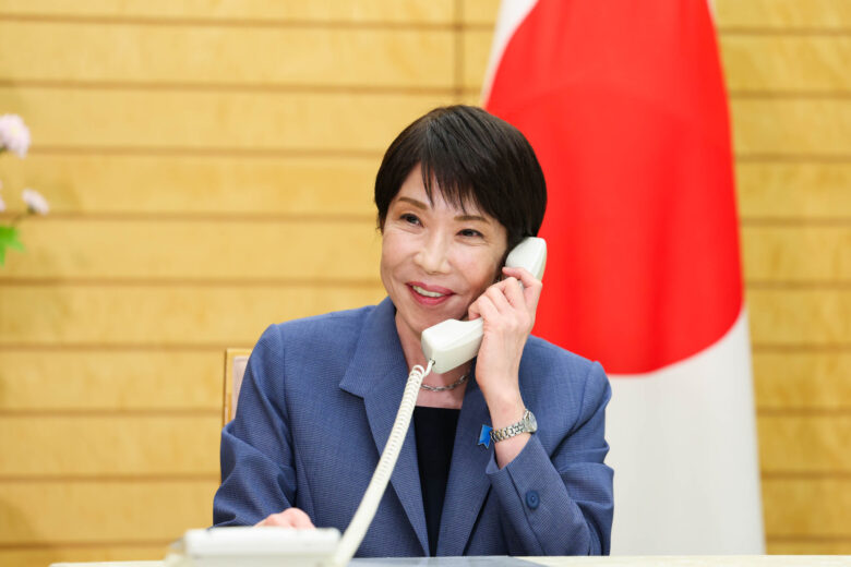 日の丸の前で電話をしながら笑顔を見せる高市早苗首相(孫は中国の大学へ留学)